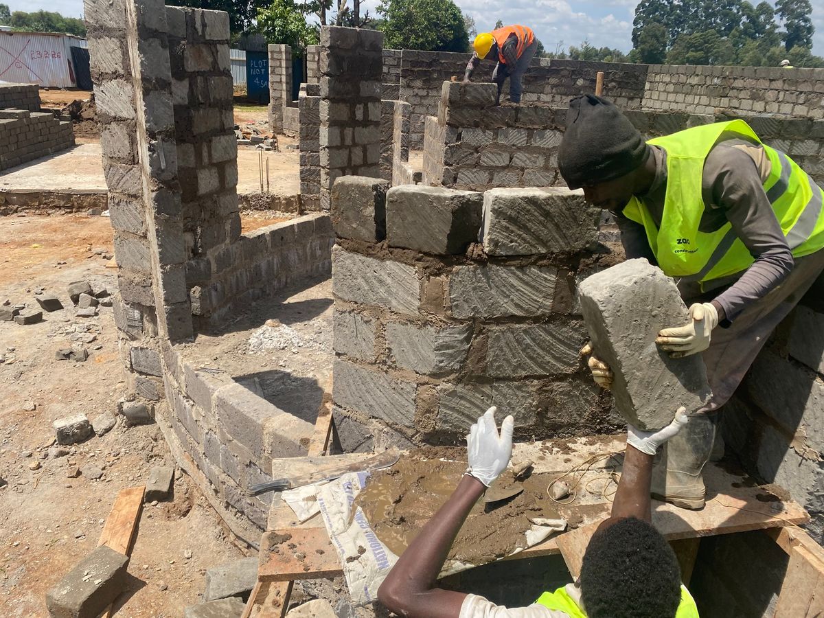 Two masons laying concrete blocks on a Zao Construction site